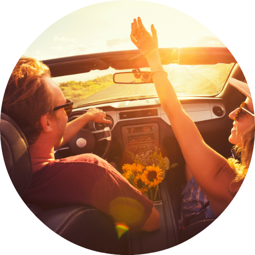 man and woman enjoying the sun and open air in a convertible