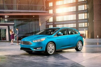 2017 Ford Focus Hatchback parked in front of a man and woman talking in front of a modern building