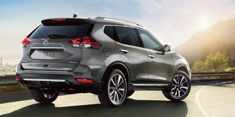 Nissan Rogue on a winding road with a city skyline