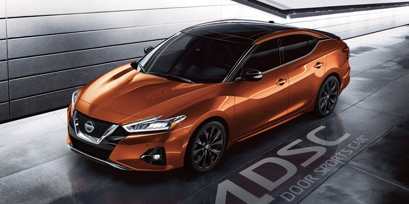 Nissan sedan with a black roof and windows sits in a garage