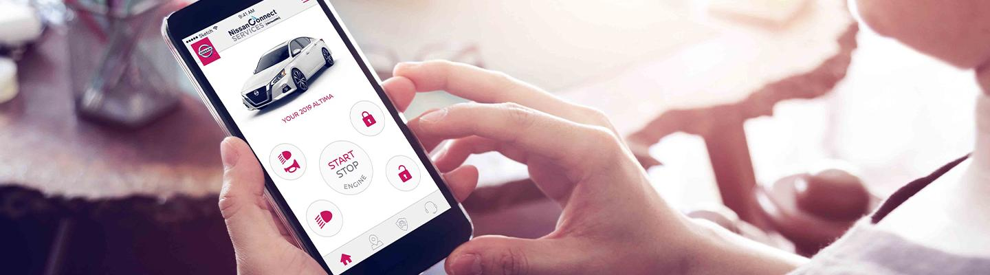 Person using NissanConnect app on phone, showing a white 2019 Altima and control icons.