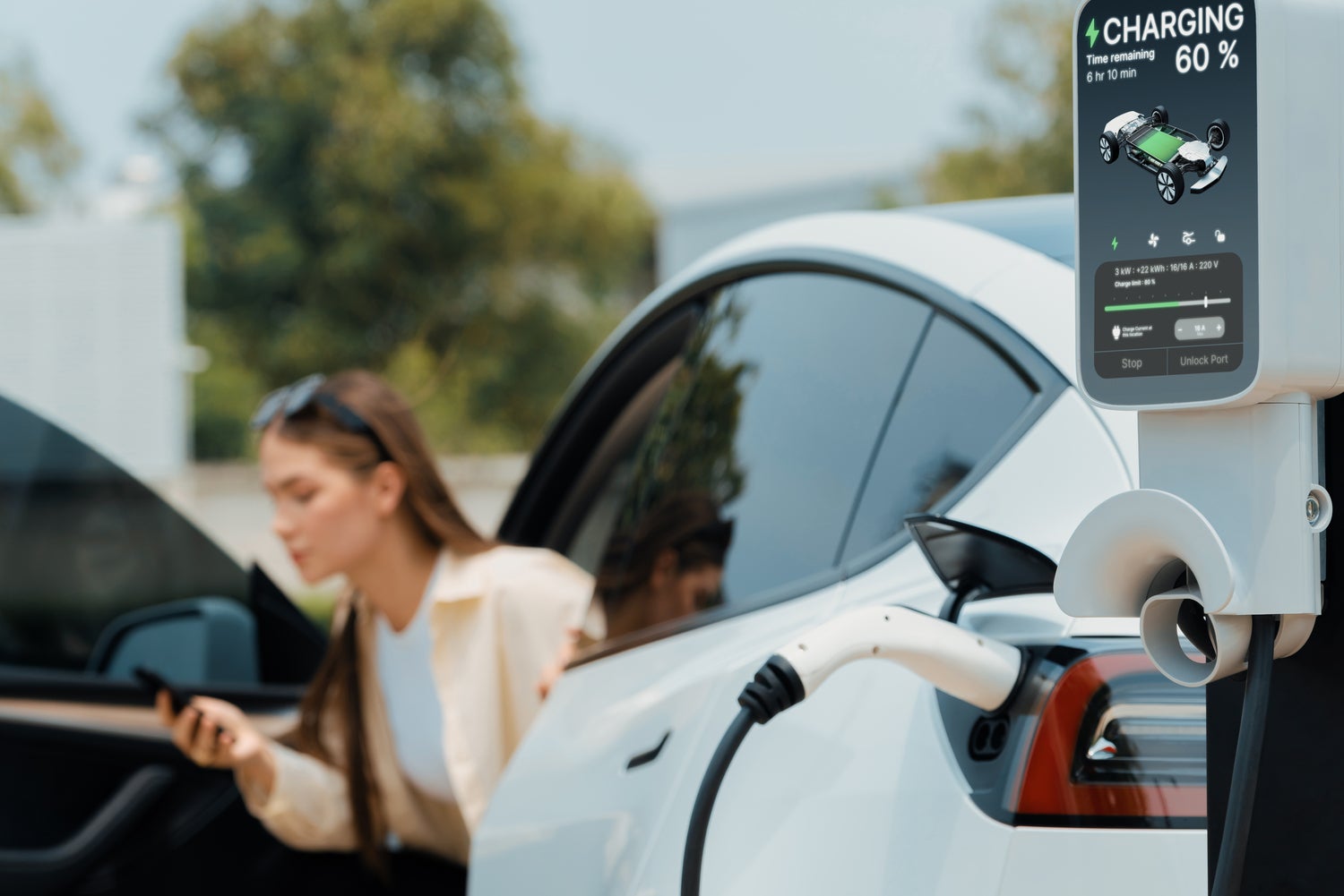Woman waiting while her electric vehicle charges at station