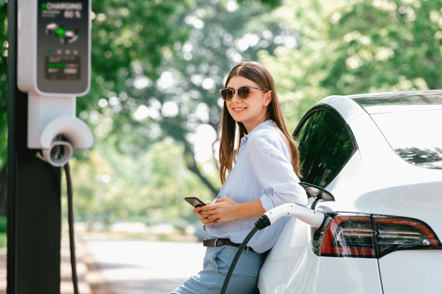 young woman using smartphone to pay for electric vehicle charging station