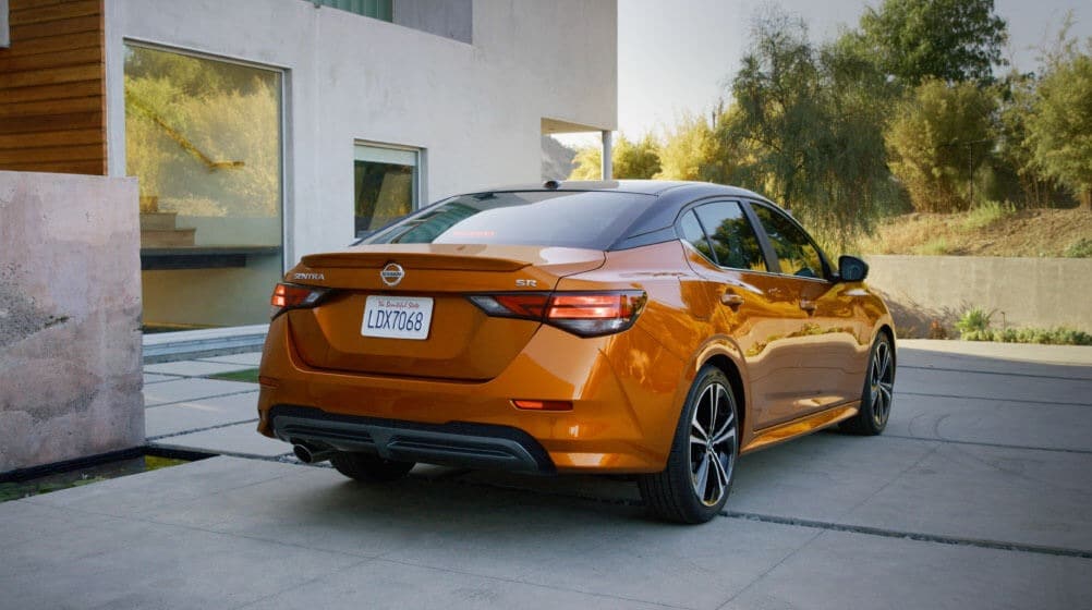 An orange 2022 Nissan Sentra parked on a driveway outside of a home