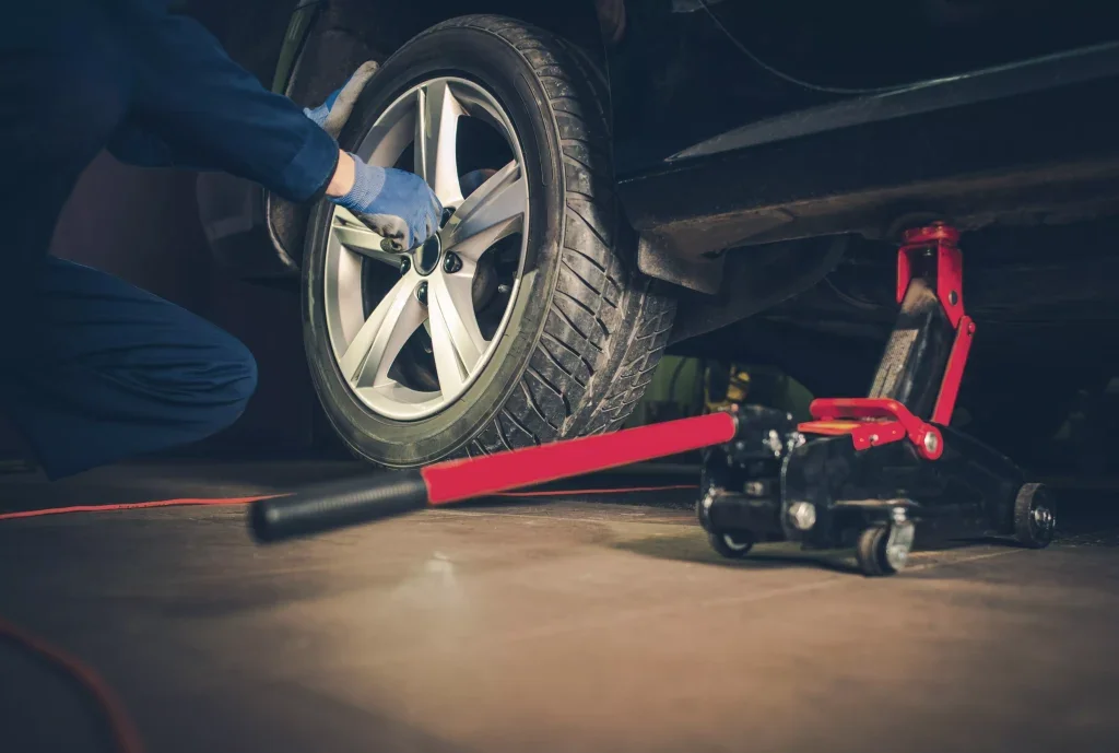 Technician inspecting and rotating a car tire in a service shop.