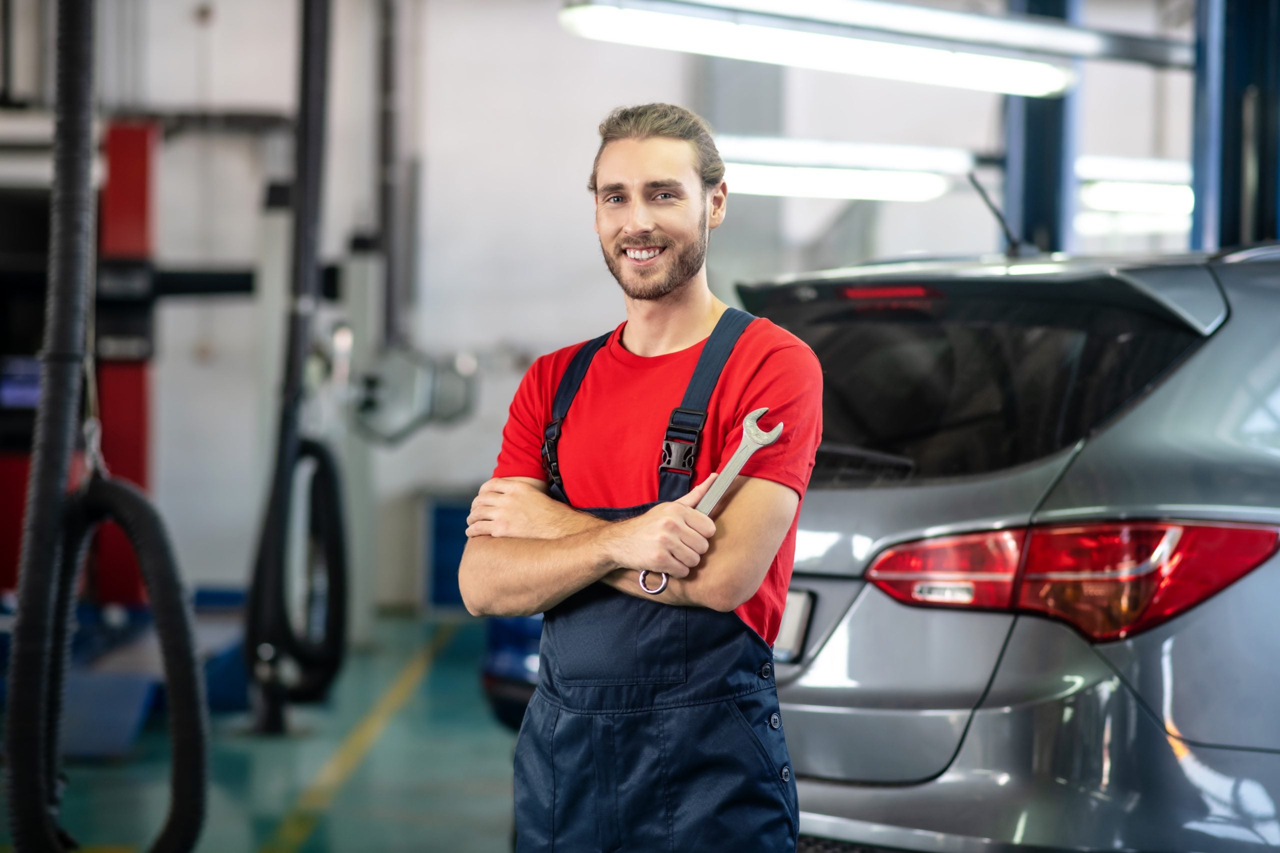 Auto technician with wrench near car.