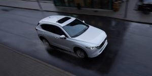 white mazda cx5 driving down a wet road
