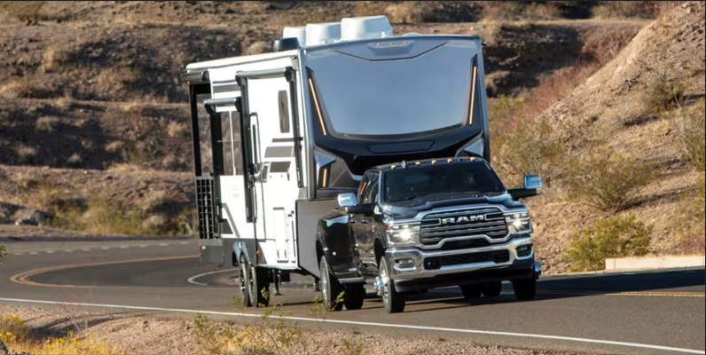 RAM pickup truck towing a large travel trailer on a winding mountain road