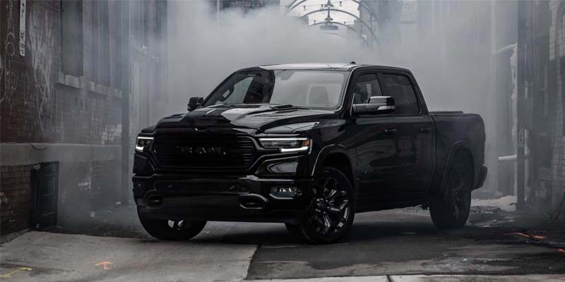 Black RAM pickup truck parked in a narrow urban alleyway surrounded by smoke or fog, creating a dramatic, moody atmosphere.