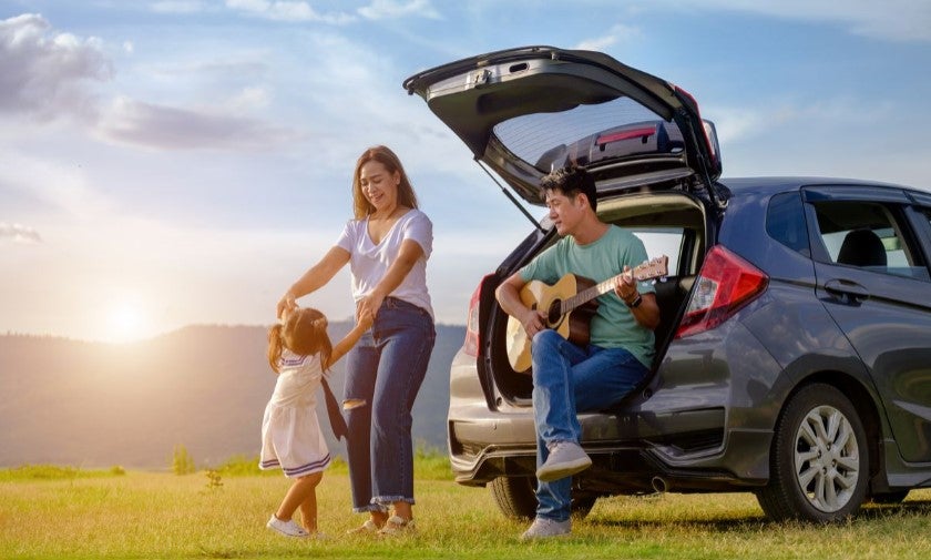 Family enjoying outdoor activity beside a parked SUV vehicle with open trunk.