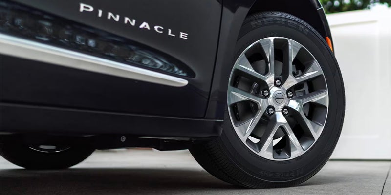 A black car's side, showing a silver "PINNACLE" badge, a chrome trim strip, and a two-tone wheel.