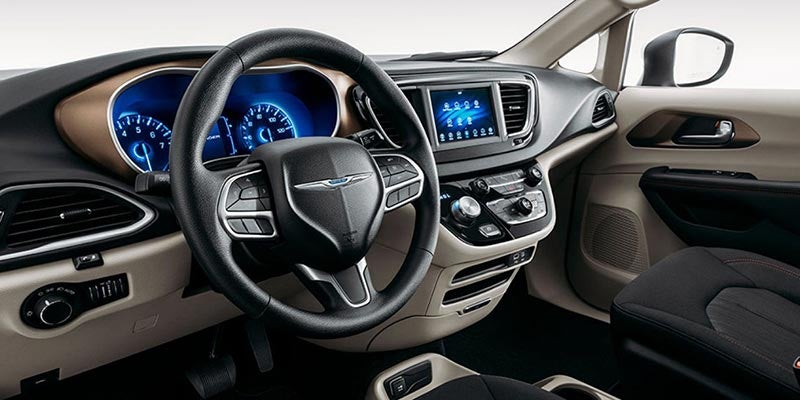 Interior view of a car cockpit, showing the steering wheel, illuminated dashboard, and infotainment screen.