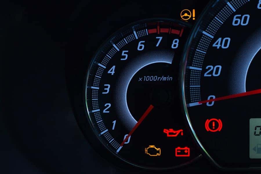 Car dashboard with tachometer, speedometer, and warning lights for steering assist, oil, engine, and battery.