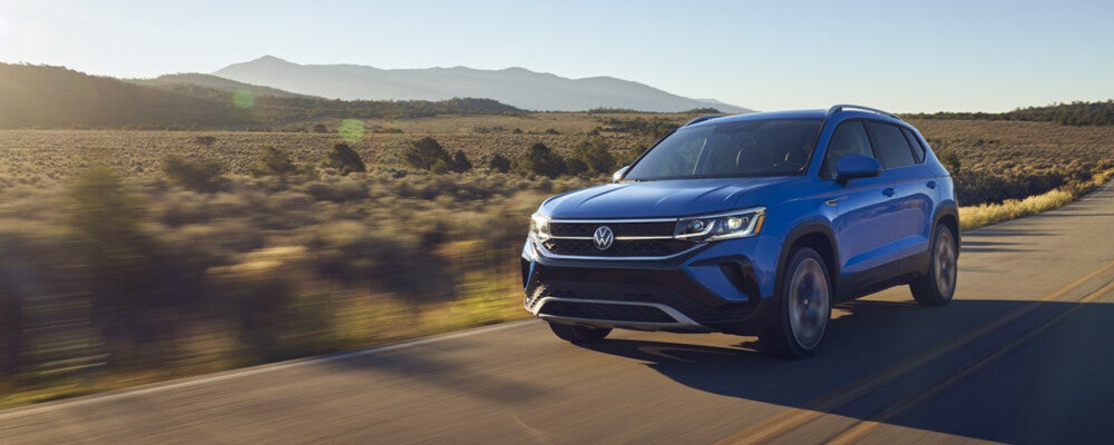 a blue volkswagen drives down a country road 