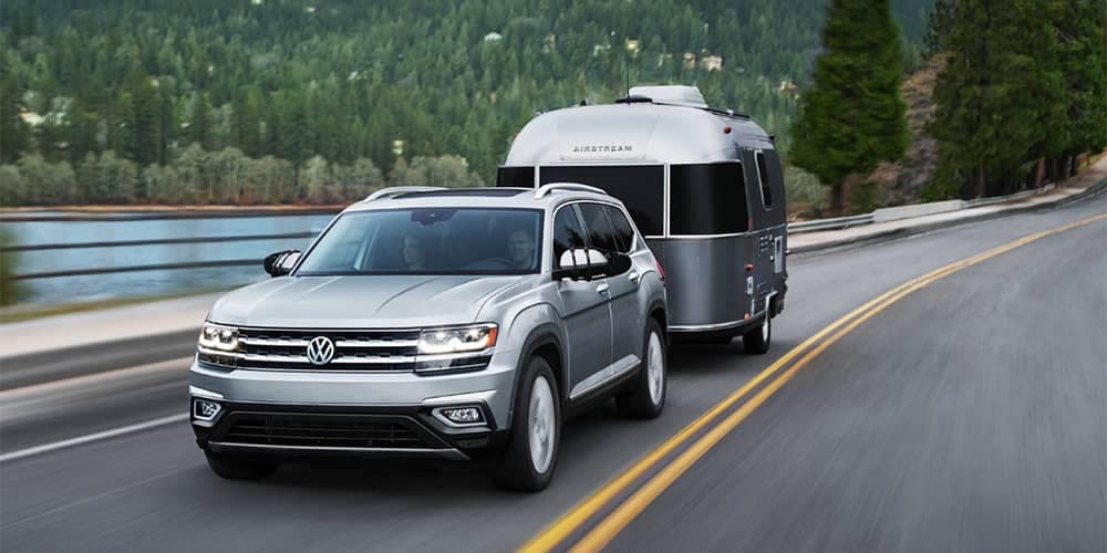 Silver Volkswagen atlas towing a small camper 