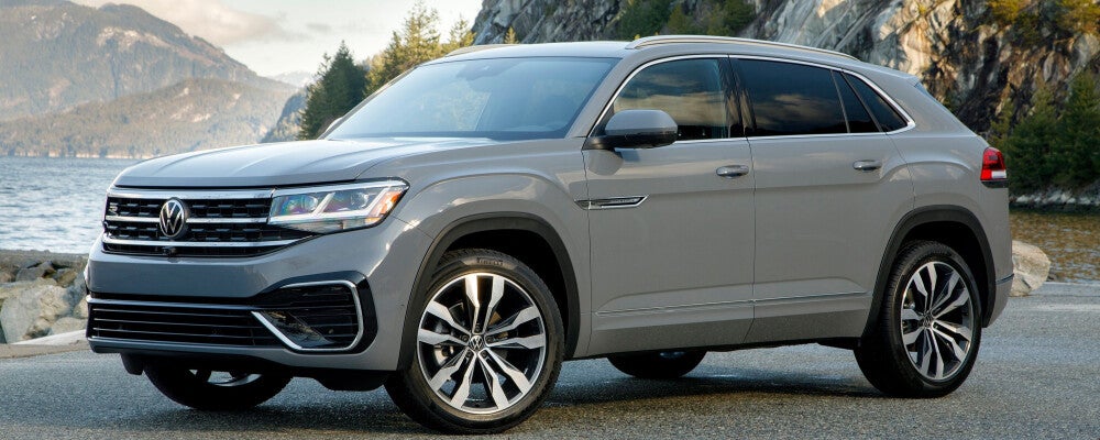 a grey volkswagen suv parked in front of a mountain landscape 