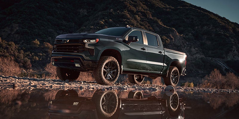 a 2025 Chevrolet Silverado 1500 parked on a dirt road next to a large puddle