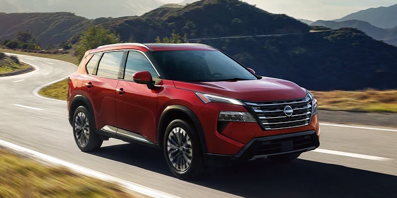 A red 2024 Nissan rogue driving down a curvy road