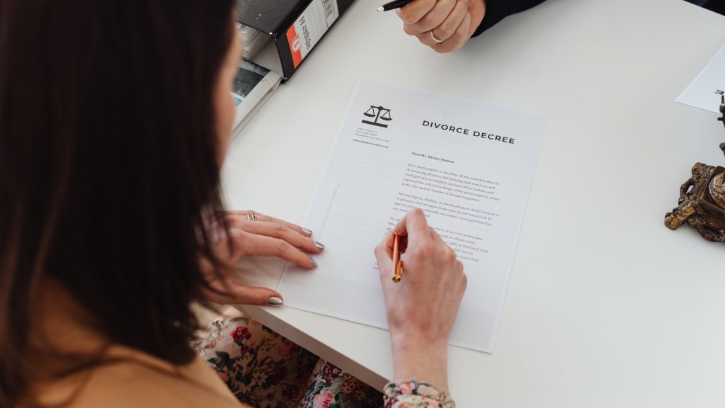 overhead shot of a brunette woman signing divorce papers