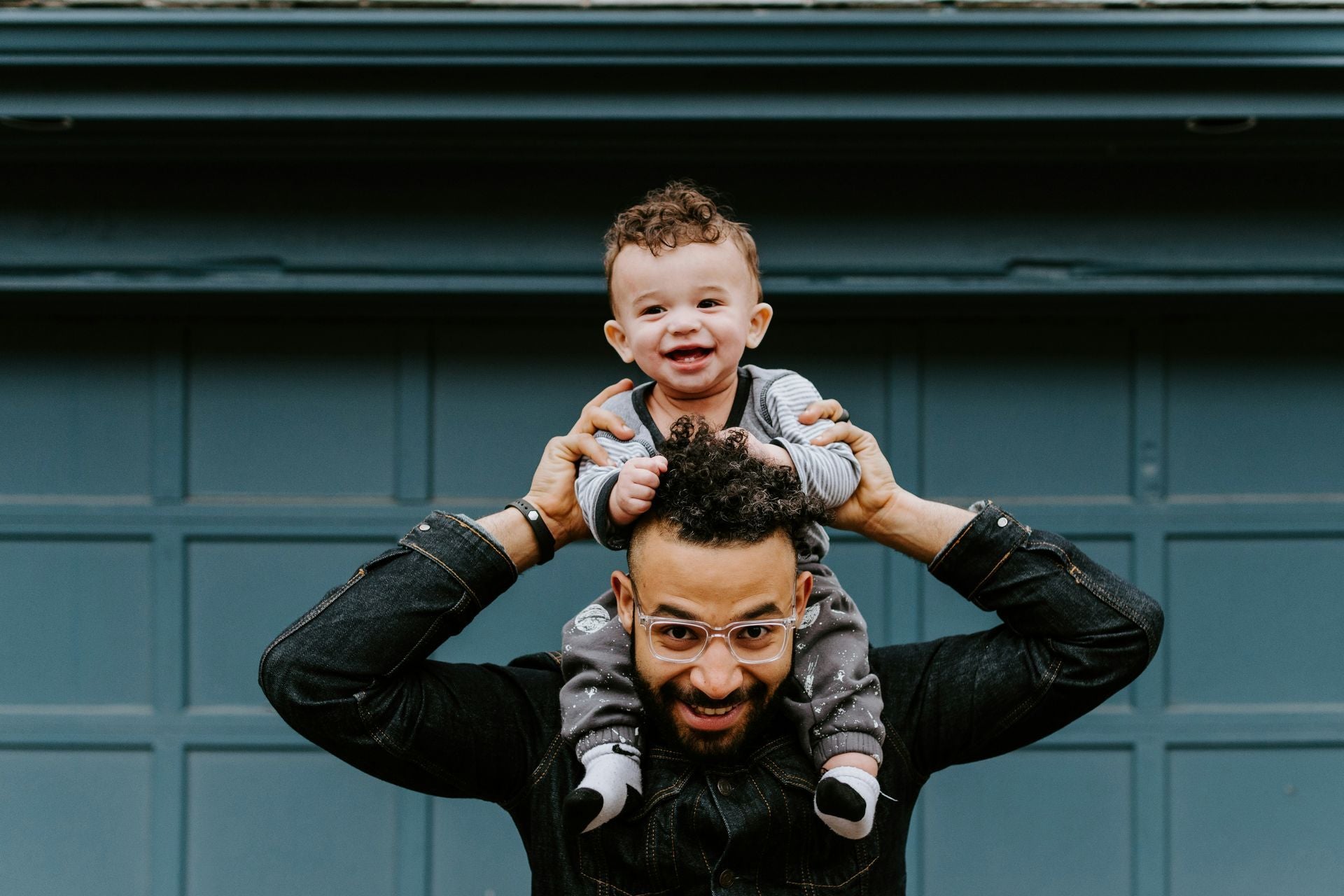 a small smiling child sits on his fathers shoulders