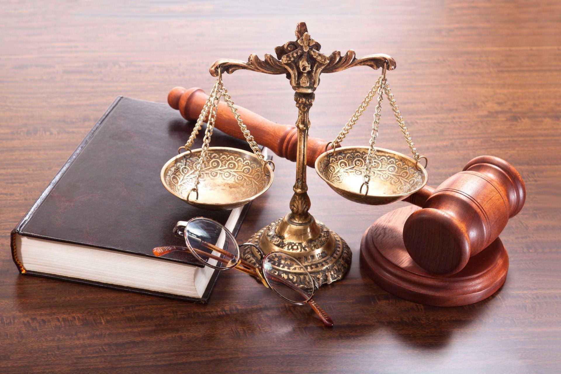 a golden scale sits on top of a black book with a gavel behind it