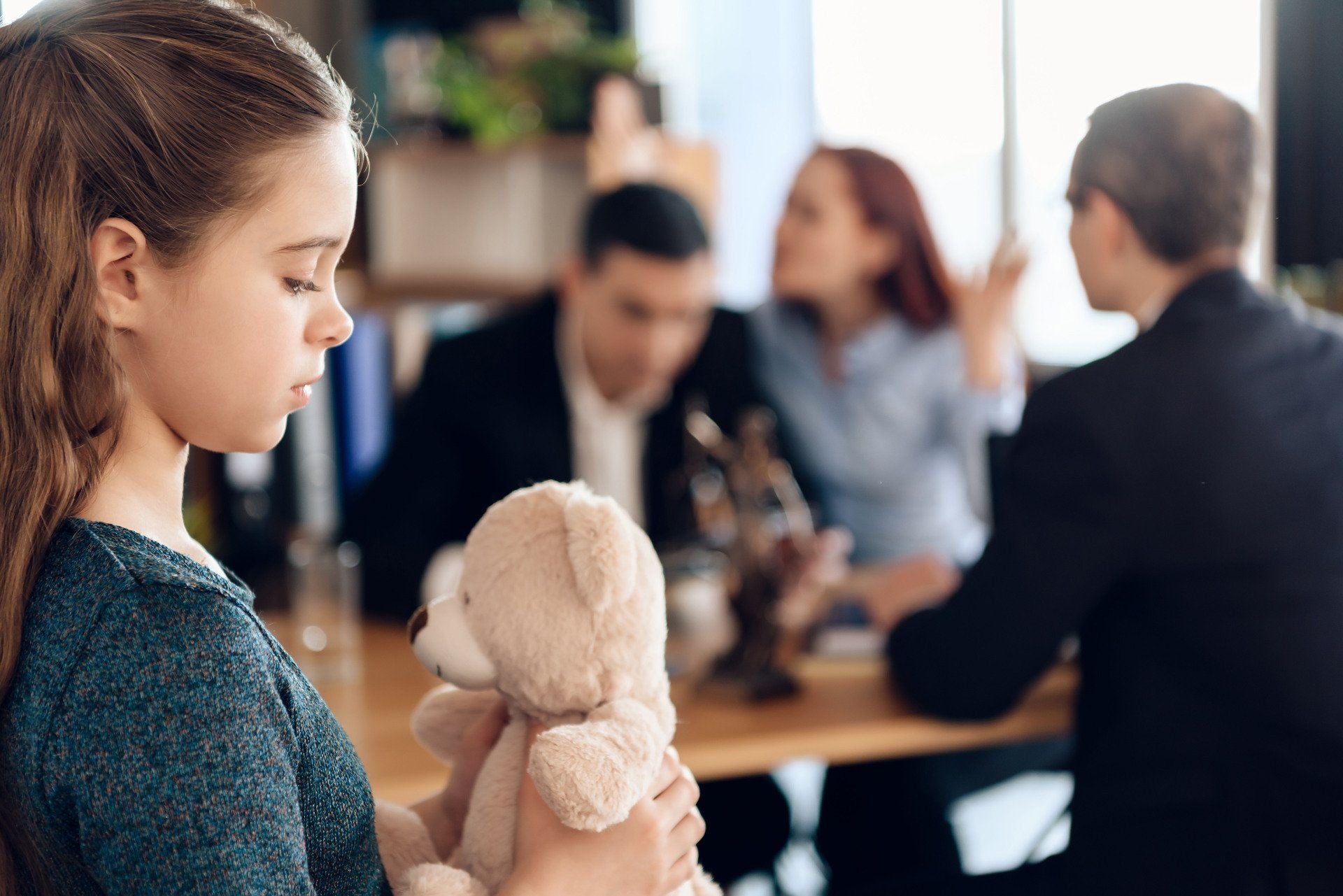a child stares at a bunny while her parents argue in the background