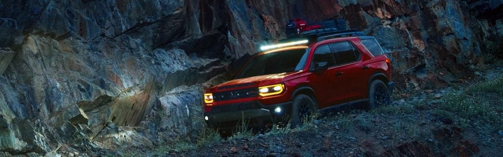 Red Honda Passport off-roading at night.