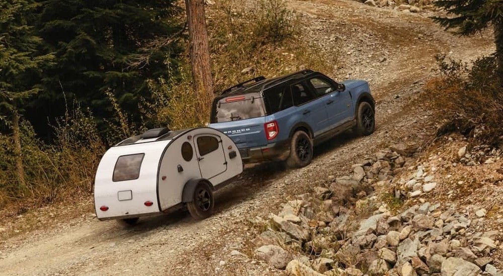 A blue 2026 Ford Bronco Sport towing a trailer offroad.