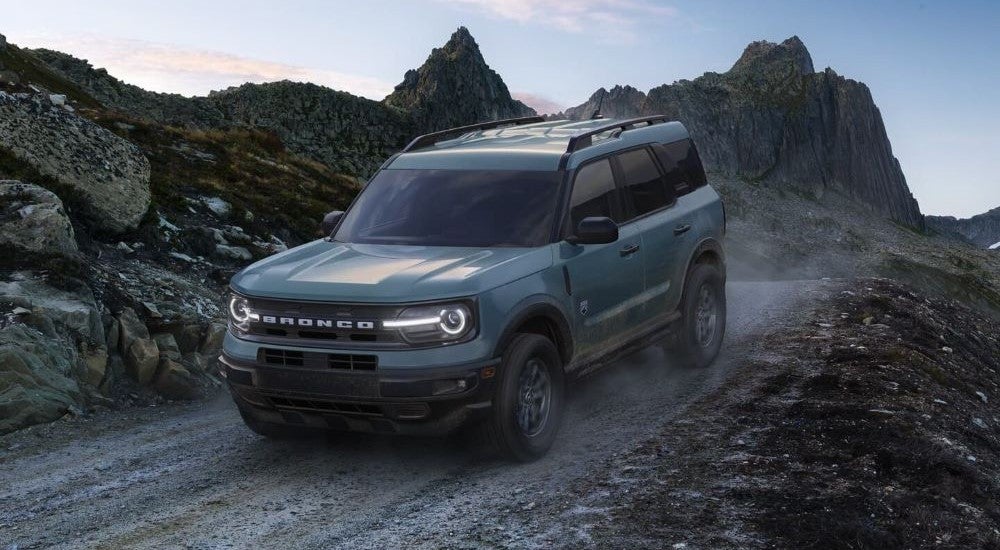 Blue 2024 Ford Bronco Sport driving down a dusty road.