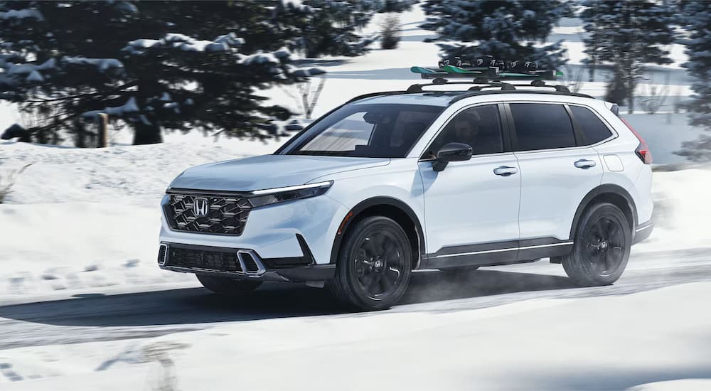 White 2025 Honda CR-V Sport Touring Hybrid for sale near Greenwood driving down a road.