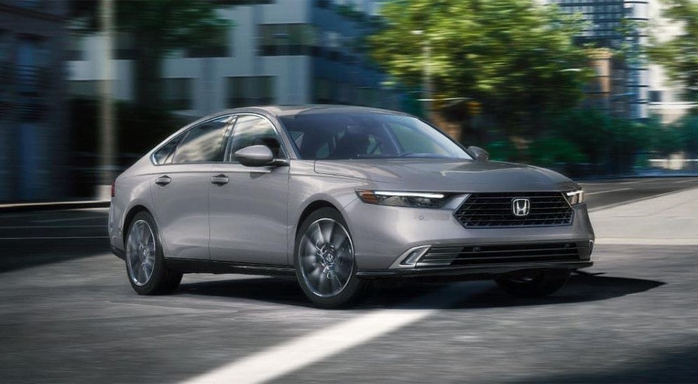 A silver 2025 Honda Accord Touring Hybrid driving to a Honda dealer near Greenwood.