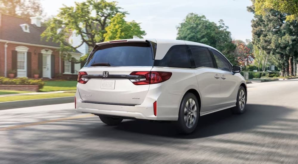 a white 2026 Honda Odyssey driving in a neighborhood.