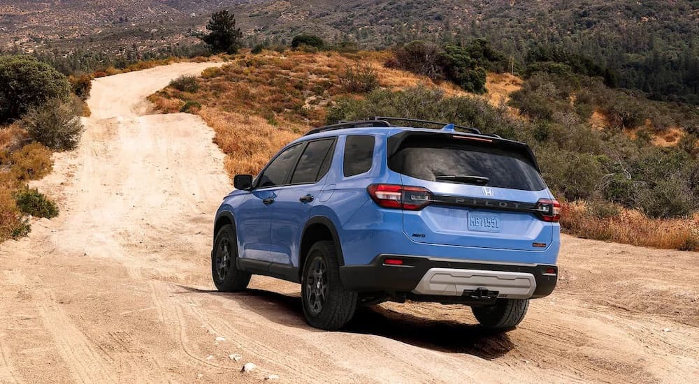 A blue 2025 Honda Pilot Trailsport is shown from the rear at an angle.