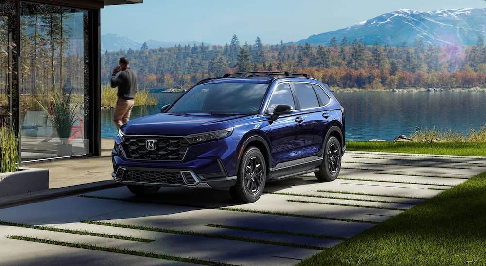 A blue2025 Honda CR-V Sport Touring Hybrid parked near a lake.