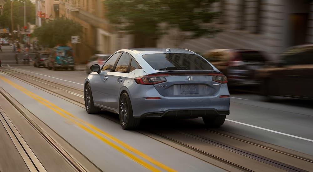 A grey 2025 Honda Civic Hatchback is shown from the rear at an angle.