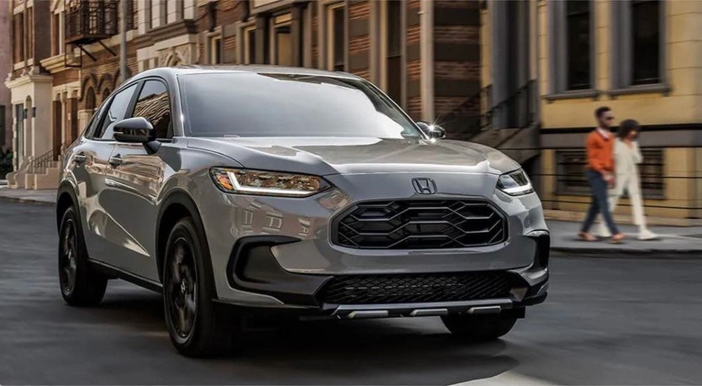 A grey 2025 Honda HR-V Sport driving to a Honda dealer.