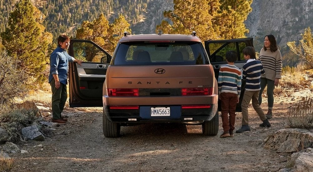 A bronze 2025 Hyundai Santa Fe is shown from the rear.