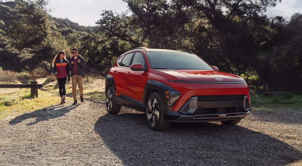 Red 2026 Hyundai Kona parked near a trail with a couple walking toward it.