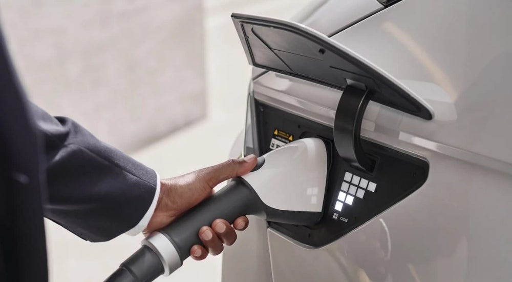 A close up shows a person charging a white 2023 Hyundai IONIQ 5.