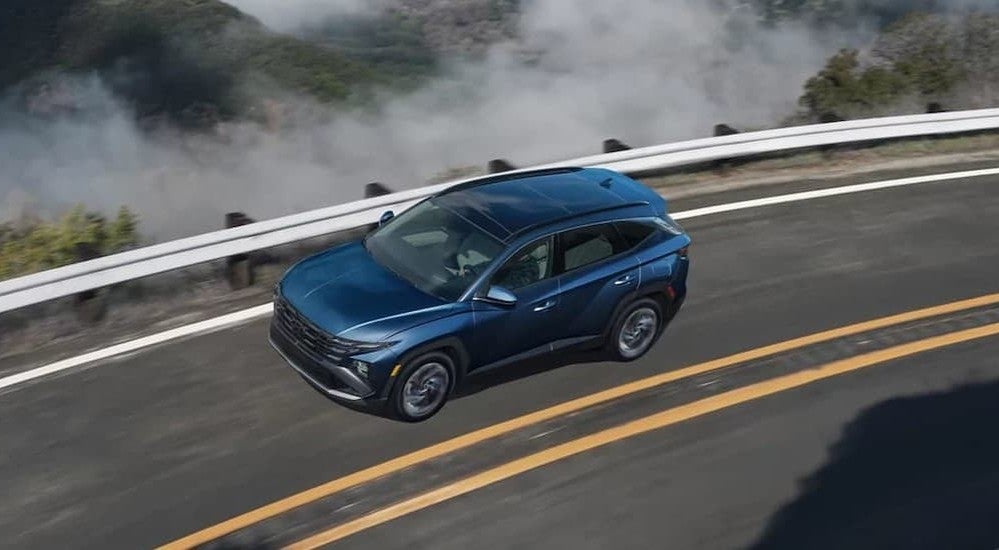 A blue 2026 Hyundai Tucson driving on a highway.