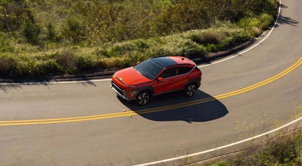 Red 2026 Hyundai Kona aerial view while driving on a paved road.