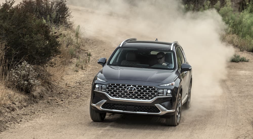 A black 2022 Hyundai Santa Fe driving down a dirt road.