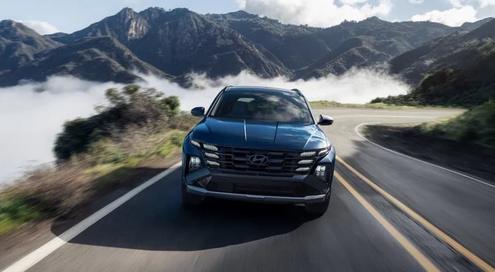 A blue 2026 Hyundai Tucson driving on a highway.