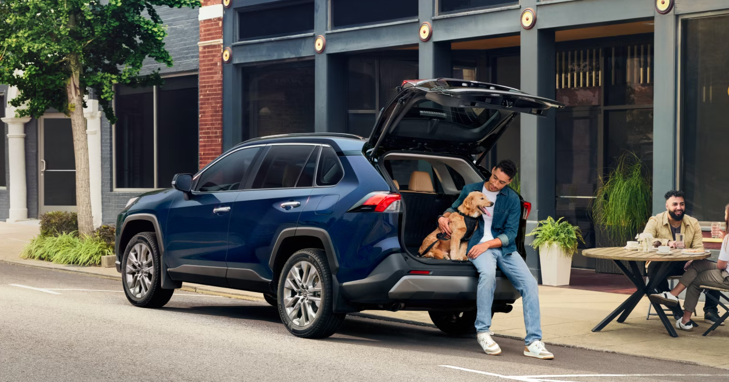 Man and his dog sitting in the trunk of a Used Toyota SUV from Oakbrook Toyota in Westmont