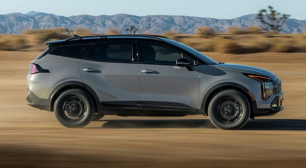 Grey 2026 Kia Sportage driving down a trail
