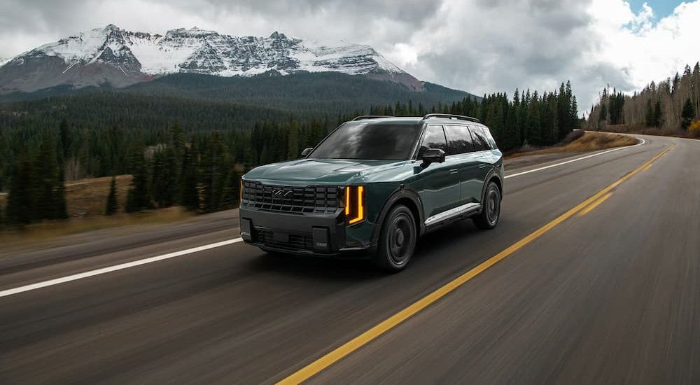 A green 2027 Kia Telluride driving on a highway.