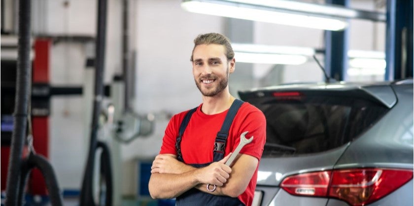 Automotive technician holding a wrench in a vehicle service center
