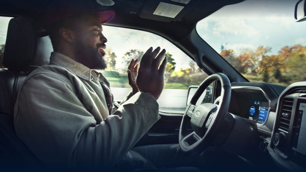 Driver enjoying the interior features of a Ford vehicle while on the road