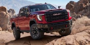 2025 GMC Sierra 2500 HD driving through the rocky terrain. 