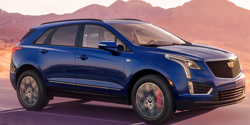 Blue Cadillac XT5 driving through a scenic desert landscape